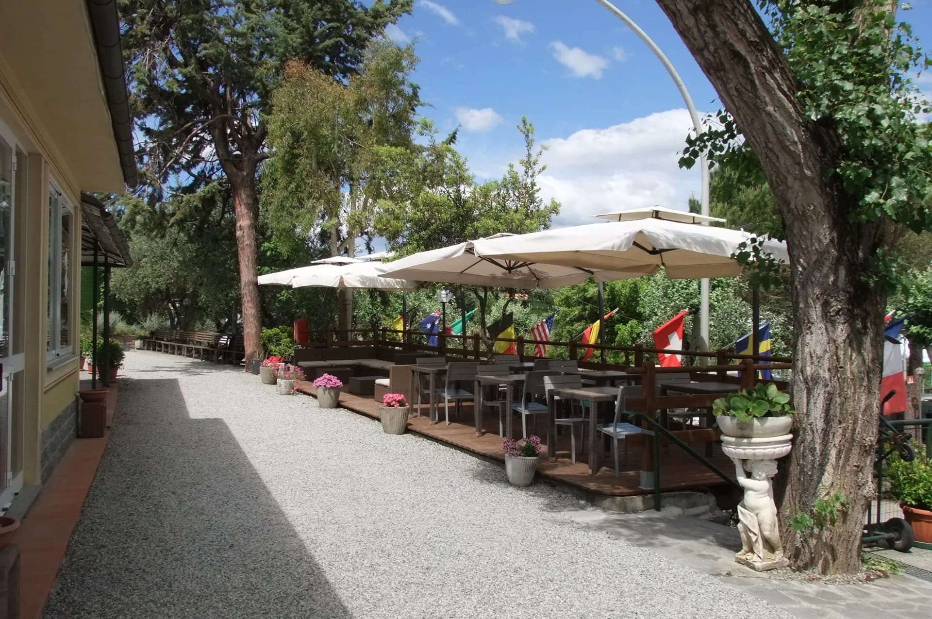 Campsite terrace with tables, parasols and trees